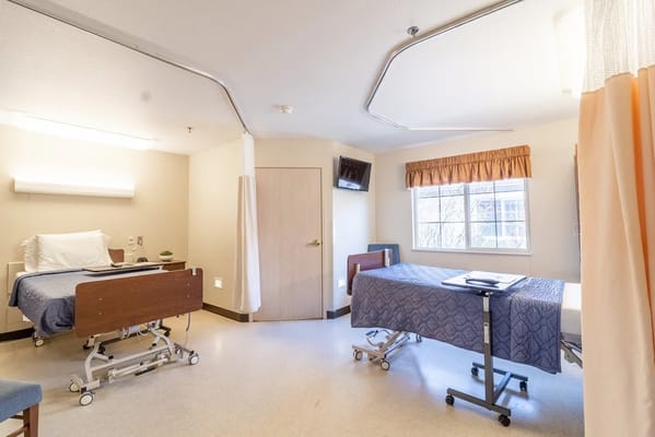 A cozy resident room with two beds and a window