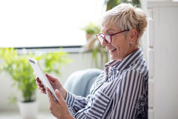 Senior woman happily using a tablet in a cozy interior