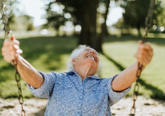 Senior woman joyfully swinging in the park