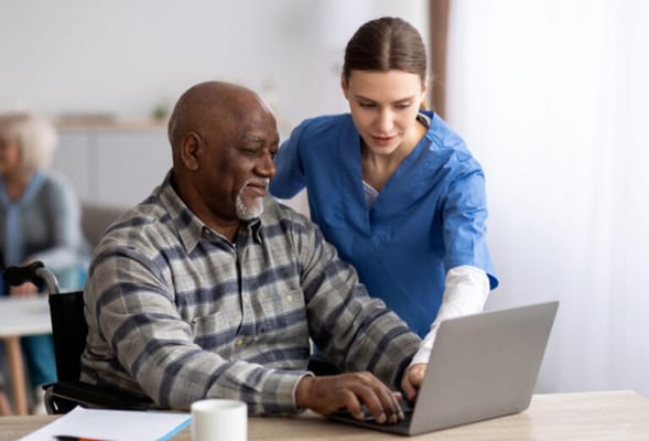 Caregiver assisting a resident with a laptop