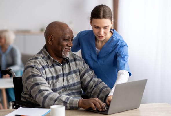 Caregiver assisting a resident with a laptop