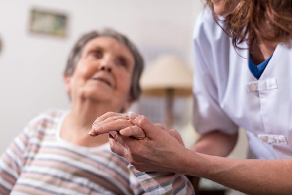 Caregiver holding a senior resident's hand