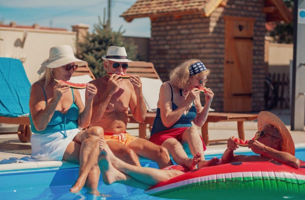 Seniors enjoying watermelon poolside on a sunny day