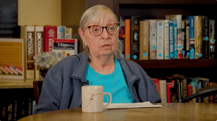 Resident in a common area with bookshelves in the background