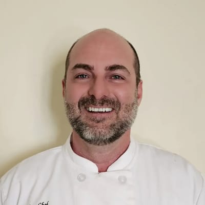 Chef smiling in a white kitchen uniform