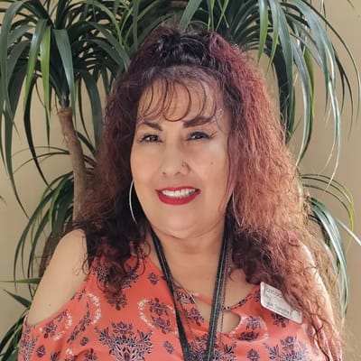 Smiling staff member with curly hair and a floral shirt
