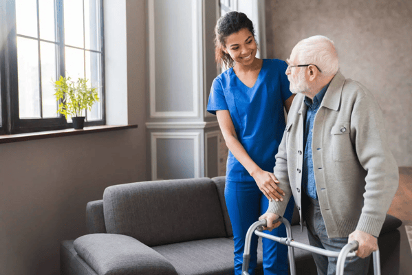 Caregiver assisting an elderly man indoors