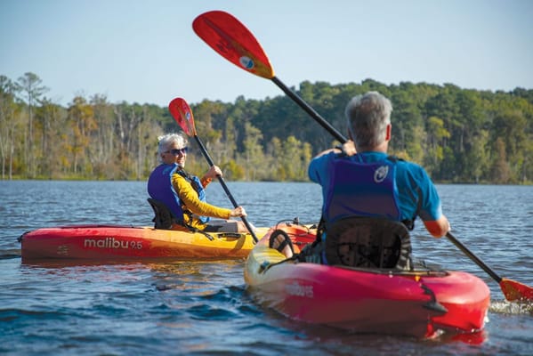 Two seniors kayaking on a calm lake