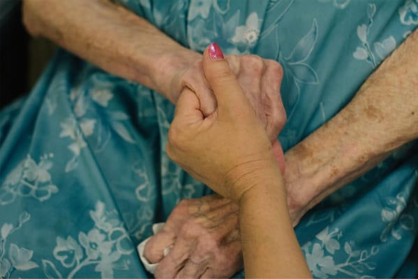 A caregiver holding a senior resident's hand