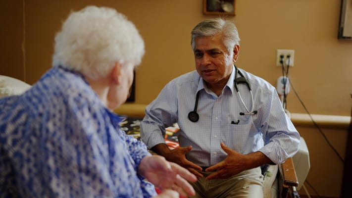 A doctor speaking with a female resident in a facility