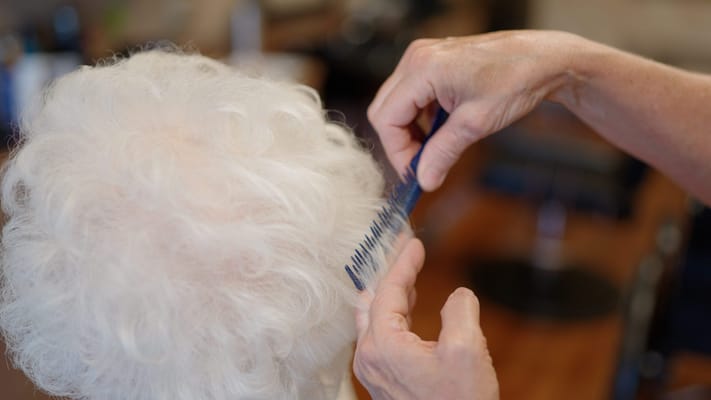 Hair stylist combing a resident's curly hair