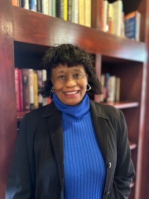 Woman smiling in front of a bookshelf in a lobby