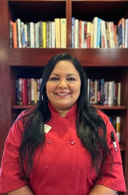 Staff member smiling in front of bookshelves