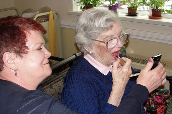 A caregiver feeding a resident in a cozy interior