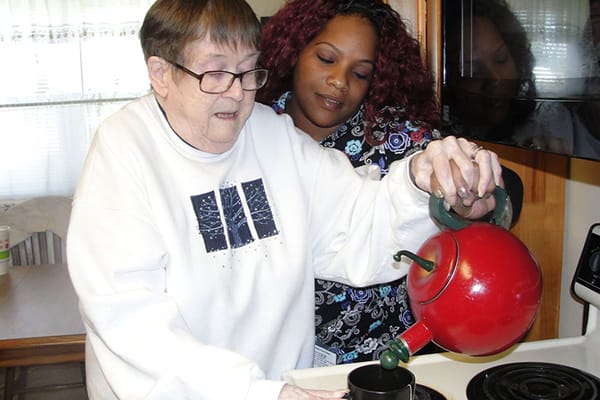 Resident and staff member in a kitchen preparing tea