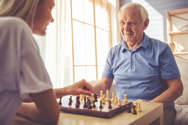 Resident and staff member playing chess indoors