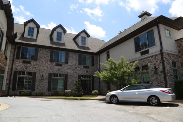Exterior view of Orchard Senior Living with landscaping and vehicle