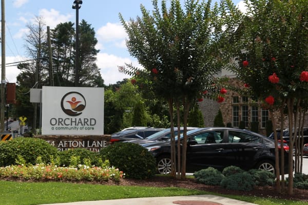 Exterior view of Orchard Senior Living sign and landscaping