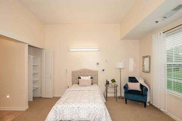 A cozy private resident room with a bed and chair