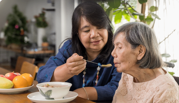 Caregiver assisting an elderly resident with a meal
