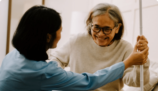 A staff member assisting a smiling resident indoors