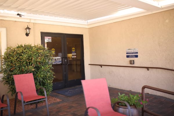 Exterior view of the entrance to Sterling Ridge Senior Living with seating area