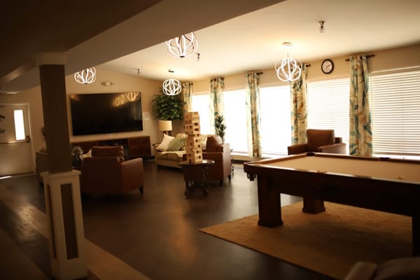 Lounge area with seating, a large TV, and games