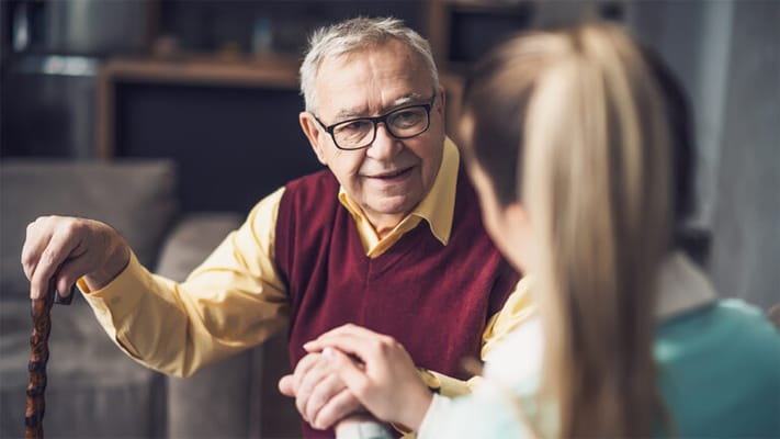 Elderly man engaging in conversation with caregiver