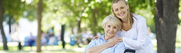 A caregiver with a resident in a sunny outdoor setting