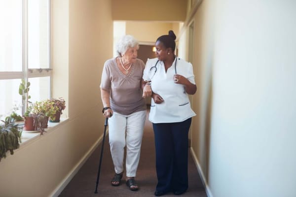 A staff member assisting a senior resident in a hallway