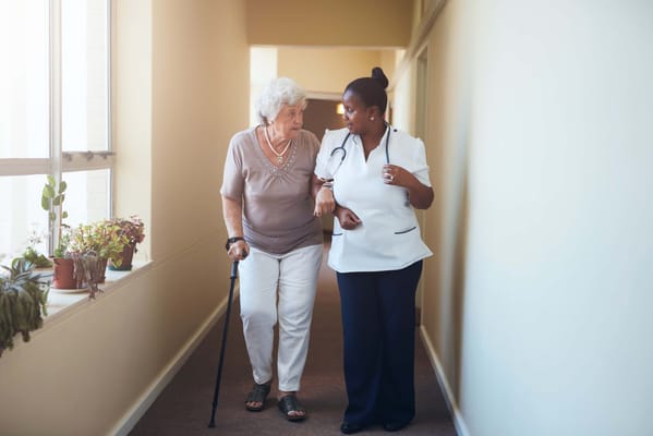 A staff member assisting a senior resident in a hallway