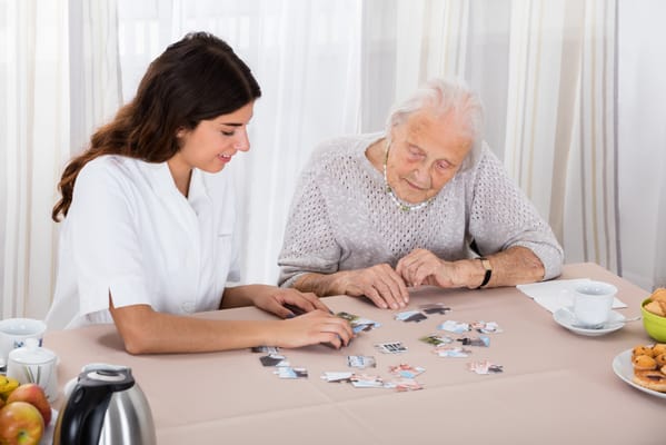 A caregiver and a resident playing a memory game at a table