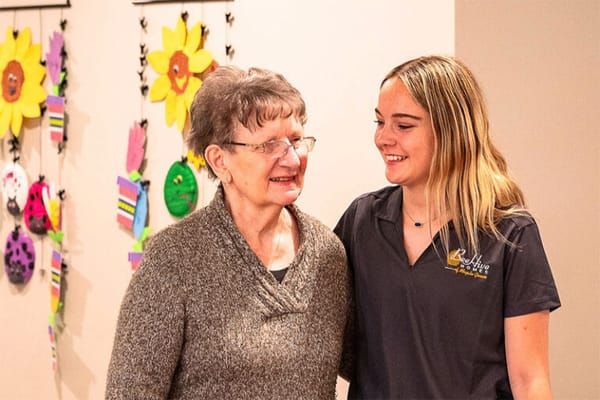 A resident and staff member smiling together indoors