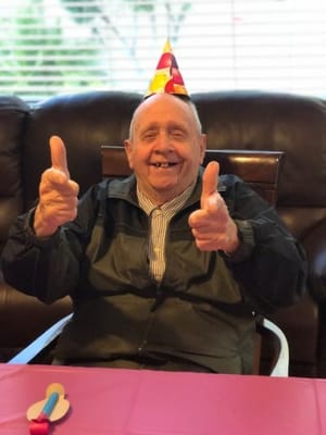 Senior resident celebrating with a party hat indoors