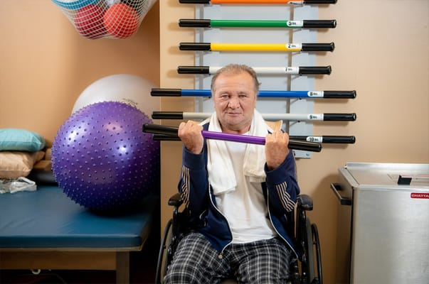 A resident using exercise equipment in a therapy room