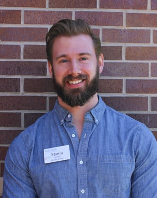 Nursing staff member smiling by a brick wall