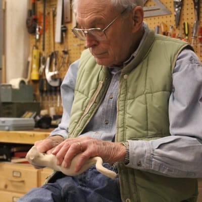 An elderly man shaping clay in a workshop