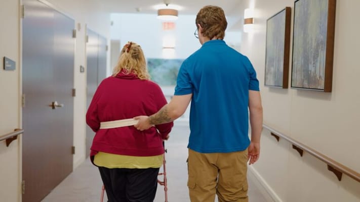 Staff assisting a resident in a hallway