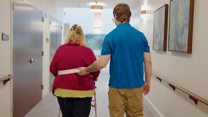 Staff assisting a resident in a hallway