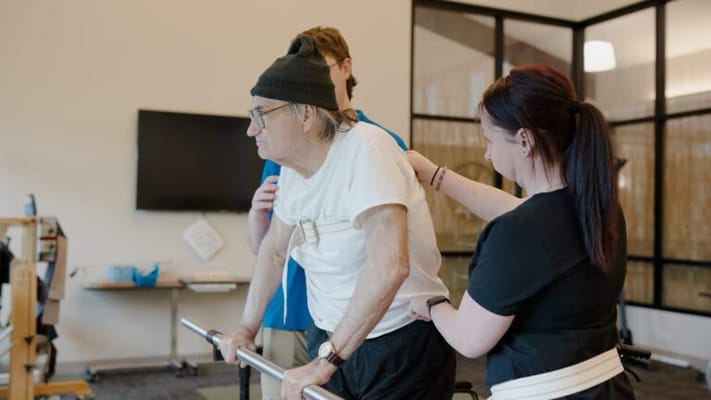 Therapists assisting an elderly man in a rehabilitation session