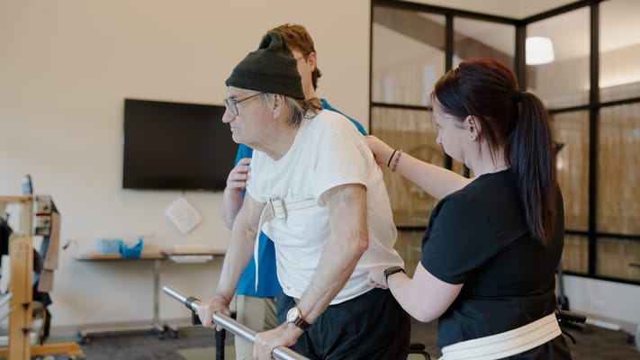 Therapists assisting an elderly man in a rehabilitation session