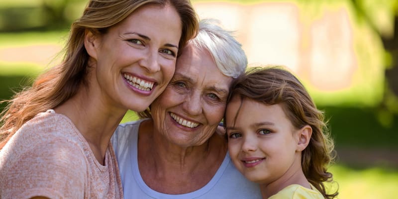 Three generations of women smiling outdoors