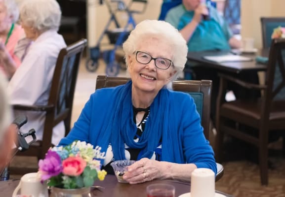 Smiling resident in a common area with flowers