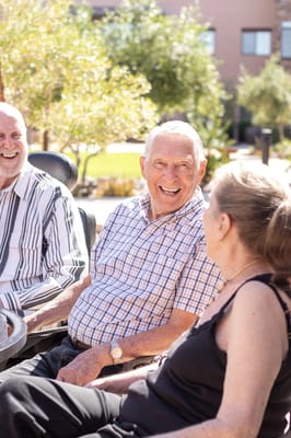 Residents enjoying conversation outdoors in a sunny garden
