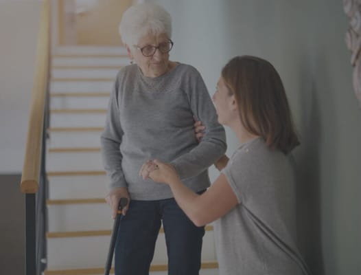 A caregiver assisting a senior woman on stairs