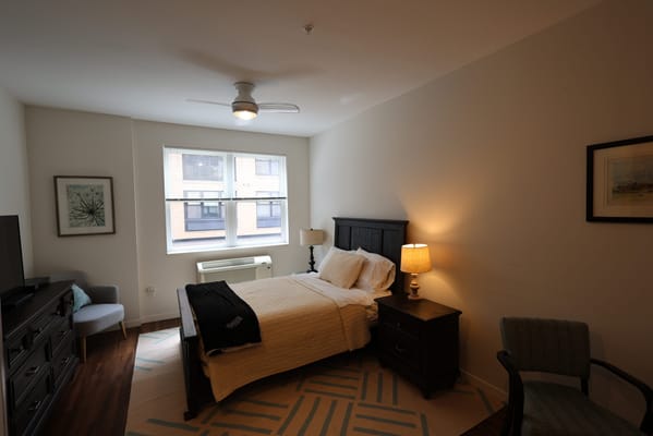 A cozy resident room with a bed and chair