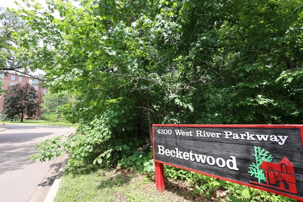 Sign indicating Becketwood with trees and road