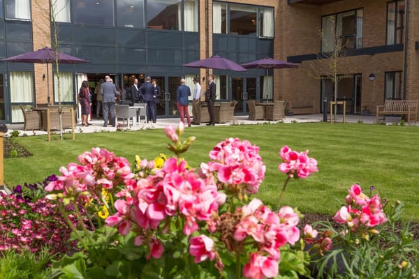 Residents and staff interacting in an outdoor garden setting