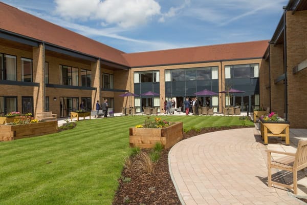 Residents and staff in a sunny outdoor courtyard