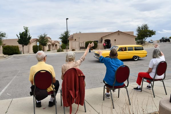 Residents waving goodbye to a departing vehicle